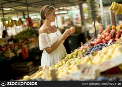 Pretty young woman buying fresh fruits on the market