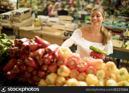 Pretty young woman buying fresh vegetables on the market
