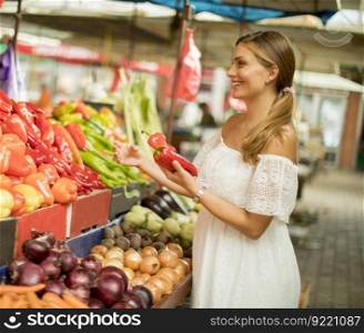 Pretty young woman buying fresh vegetables on the market