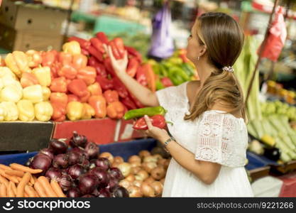 Pretty young woman buying fresh vegetables on the market