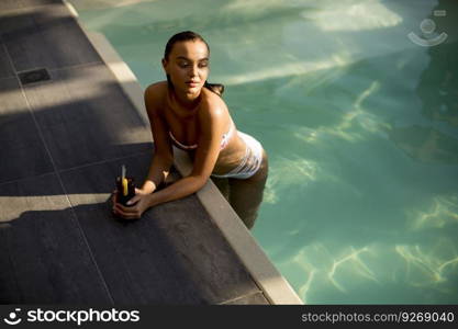 Pretty young woman by the swimming pool with coctail