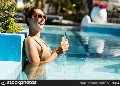 Pretty young woman by the swimming pool with coctail