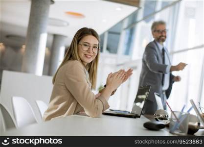 Pretty young woman clapping hands after successful business meeting in the modern office