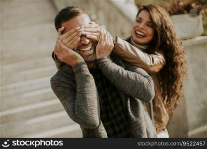 Pretty young woman covering the eyes of her boyfriend in the park