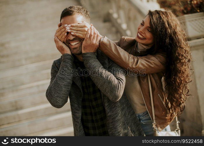 Pretty young woman covering the eyes of her boyfriend in the park