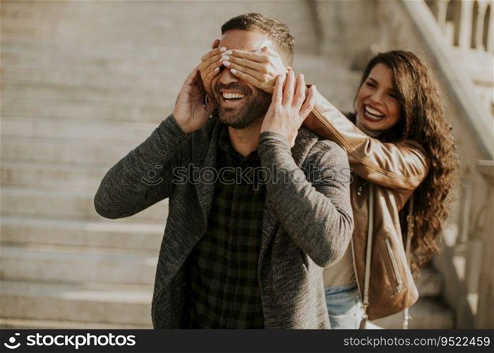Pretty young woman covering the eyes of her boyfriend in the park