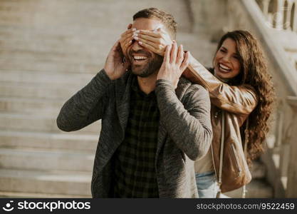 Pretty young woman covering the eyes of her boyfriend in the park