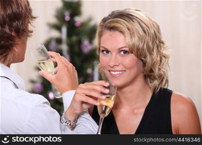Pretty young woman drinking champagne with her boyfriend at Christmas