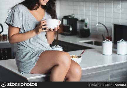 Pretty young woman drinking coffee in kitchen at home