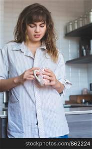 Pretty young woman drinking coffee in kitchen at home