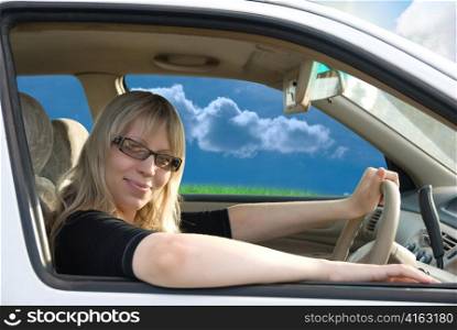 Pretty young woman driving car on nature background
