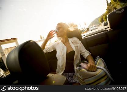 Pretty young woman driving in the cabriolet car at summer