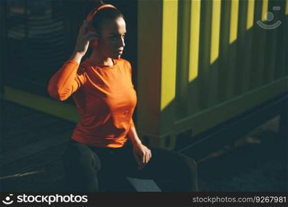 Pretty young woman having break and listening music during training