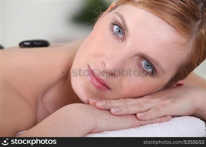 Pretty young woman having hot stones massage