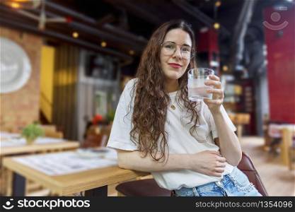 Pretty young woman holding a glass of water