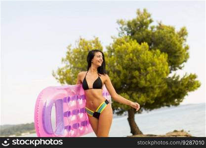 Pretty young woman holding air mattress on the beach at summer