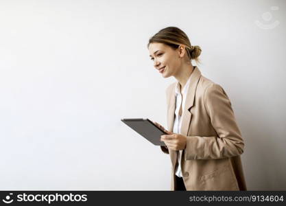 Pretty young woman holding digital tablet by the white wall in modern office