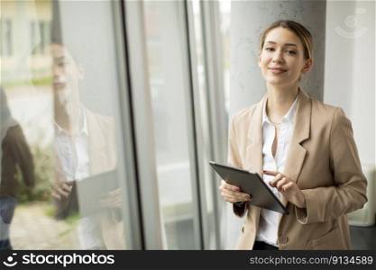 Pretty young woman holding digital tablet in modern office
