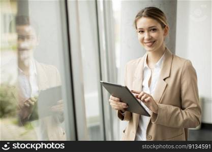 Pretty young woman holding digital tablet in modern office