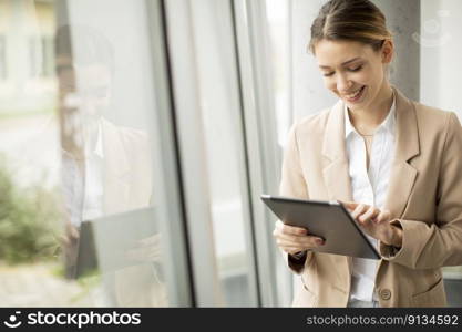 Pretty young woman holding digital tablet in modern office