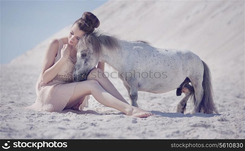 Pretty young woman hugging the white pony