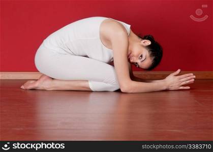 Pretty young woman in a exercise clothing in a yoga pose on floor