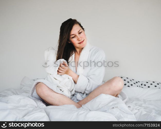 Pretty, young woman in a soft, terry dressing bathrobe, combing her hair after Spa Services and Spa Treatments. Pretty woman combing her hair after Spa