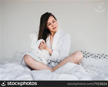 Pretty, young woman in a soft, terry dressing bathrobe, combing her hair after Spa Services and Spa Treatments. Pretty woman combing her hair after Spa