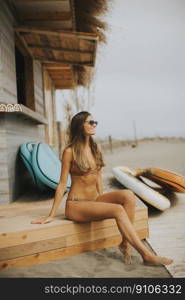 Pretty young woman in bikini sitting on the beach at summer day