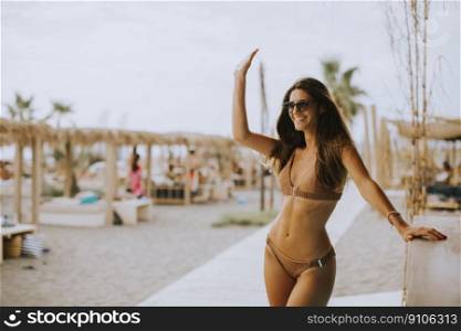 Pretty young woman in bikini standing by the beach bar on a summer day