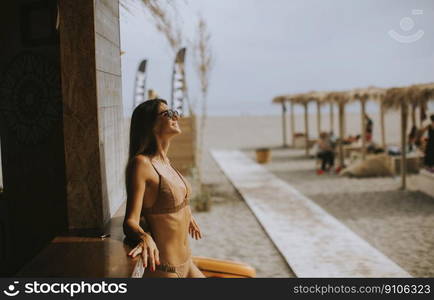 Pretty young woman in bikini standing by the beach bar on a summer day