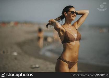 Pretty young woman in bikini standing by the sea on a summer day