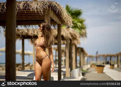 Pretty young woman in bikini standing on the beach at summer day