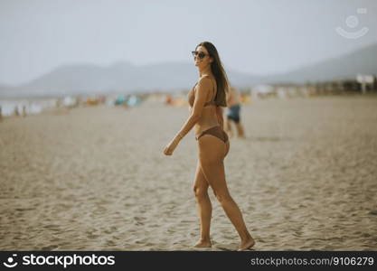 Pretty young woman in bikini walking by the sea on a summer day