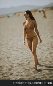 Pretty young woman in bikini walking by the sea on a summer day