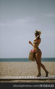 Pretty young woman in bikini walking on a beach at summer
