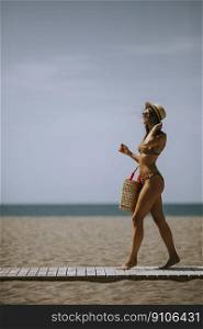 Pretty young woman in bikini walking on a beach at summer