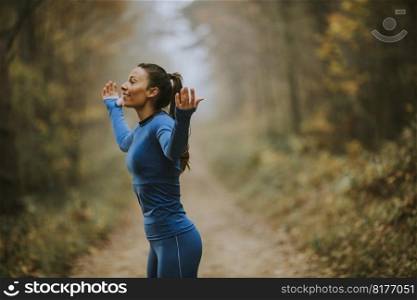 Pretty young woman in blue track suit spreading arms and taking deep breath in a forest