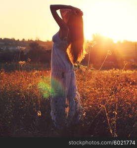 Pretty young woman in field at sunset. Photo toned style Instagram filters