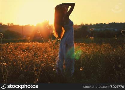 Pretty young woman in field at sunset. Photo toned style Instagram filters
