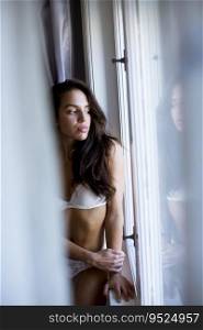Pretty young woman in lingerie standing by the window