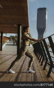 Pretty young woman in sportswear exercising on a river promenade