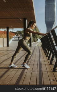 Pretty young woman in sportswear exercising on a river promenade