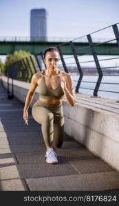 Pretty young woman in sportswear stretching on a river promenade