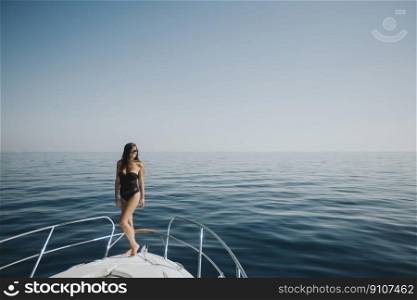 Pretty young woman in swimwear standing on yacht front