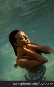 Pretty young woman in the swimming pool at hot summer day
