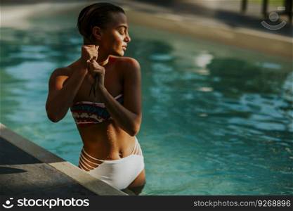 Pretty young woman in the swimming pool at hot summer day