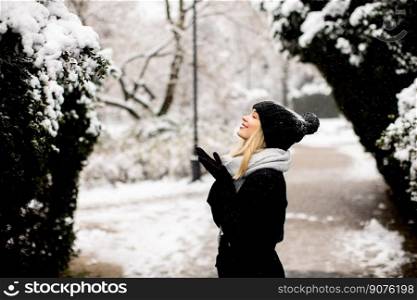 Pretty young woman in warm clothes enjoying in snow
