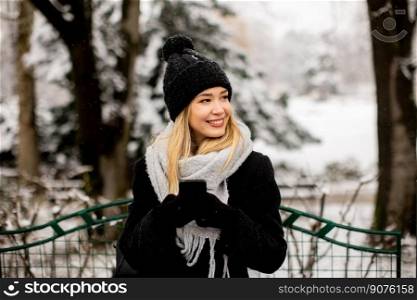 Pretty young woman in warm clothes using mobile phone on a winter day