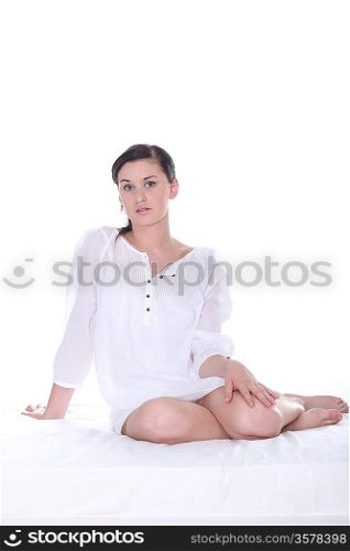 Pretty young woman in white on a white bed